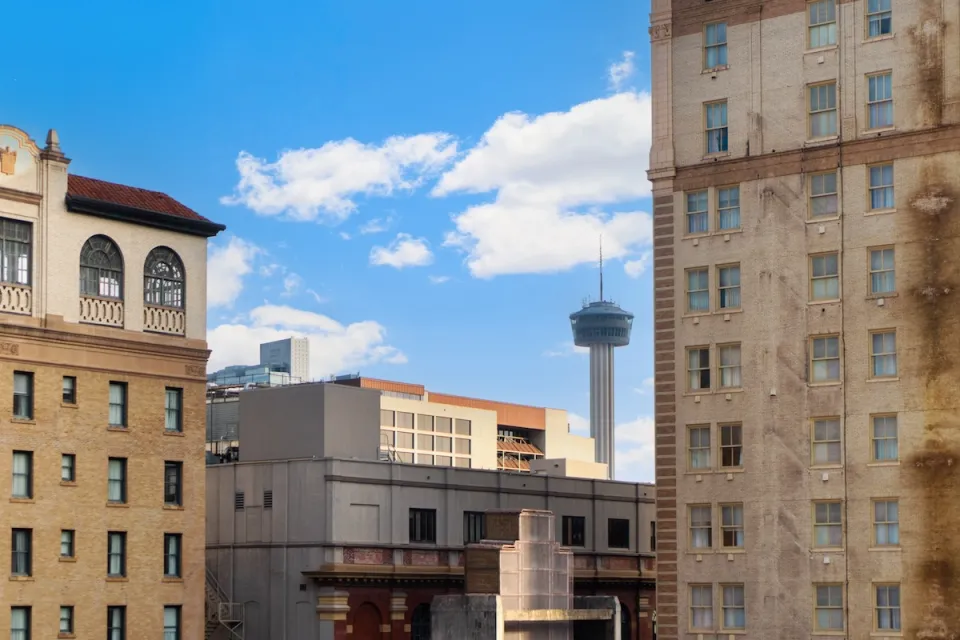 View of rotating restaurant tower in downtown San Antonio, Texas through older brick high-rise buildings.